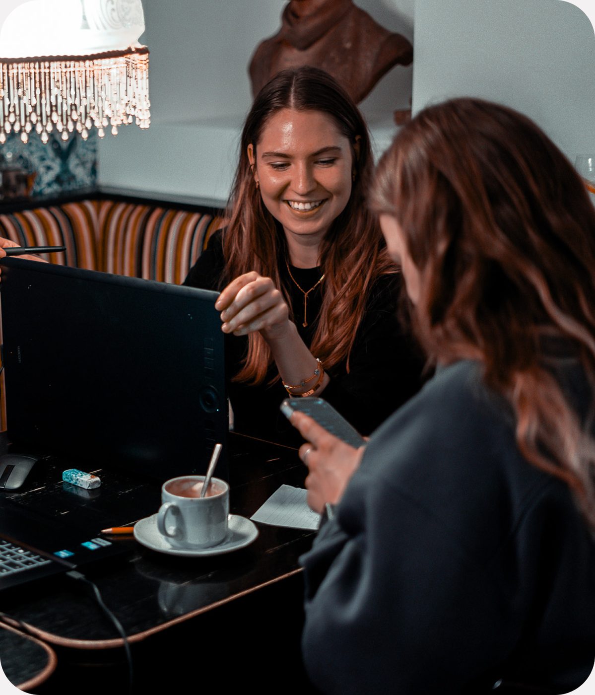 Zwei Frauen im Gespraech an einem Cafetisch mit Tablet