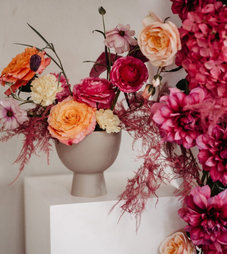 Blumenarrangement in Pink und Orange auf einem Podest